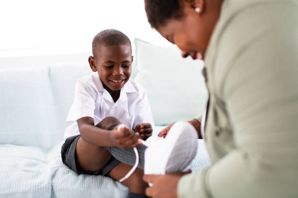 African mother fitting new school shoes on her son